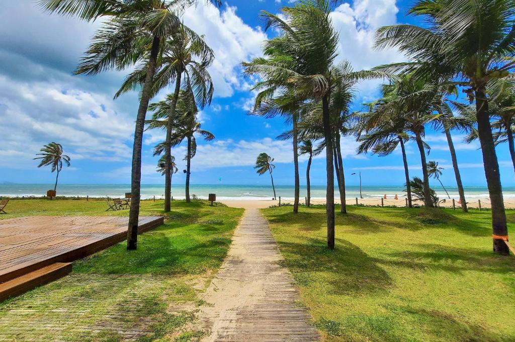a path leading to the beach with palm trees at Wai Wai Cumbuco Vista Lateral Mar 2 Quartos in Guagiru