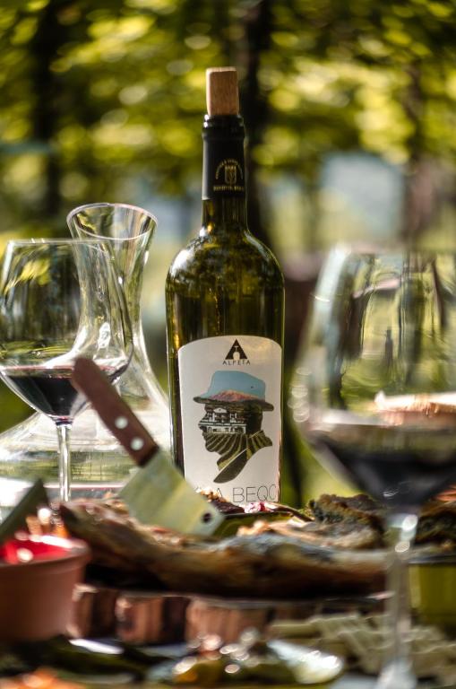a bottle of wine sitting on a table with glasses at Alpeta Agrotourism & Winery - Roshnik , Berat in Berat