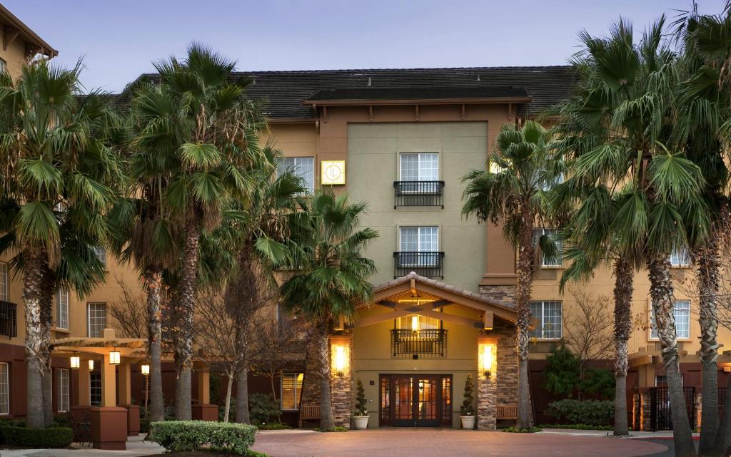 a hotel with palm trees in front of it at Larkspur Landing Extended Stay Suites Sacramento in Sacramento