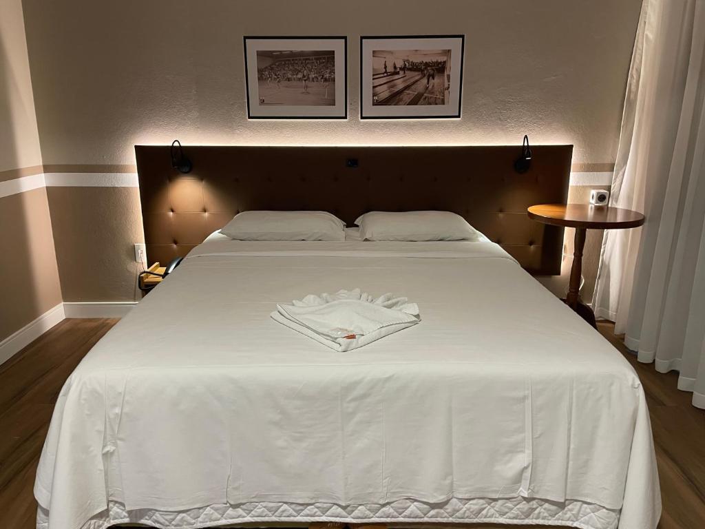 Una gran cama blanca con una camisa blanca. en Hotel Nelo, en Jaraguá do Sul