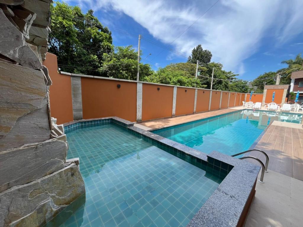 a swimming pool with a tile floor and a wall at Condomínio Apoena in São Sebastião