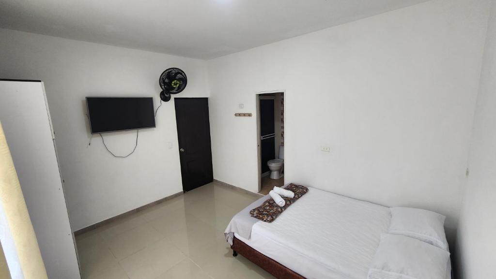 a bedroom with a bed and a flat screen tv at Hostal SHELTER LA PERLA - San luis, Antioquia, Colombia in San Luis