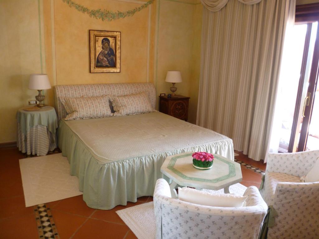 1 dormitorio con 1 cama, mesa y sillas en I Delfini di Cala del Faro, en Porto Cervo