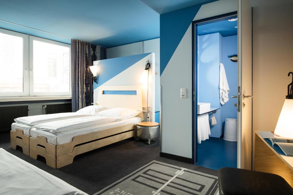 een blauwe kamer met een bed en een spiegel bij Superbude Hamburg St Georg in Hamburg