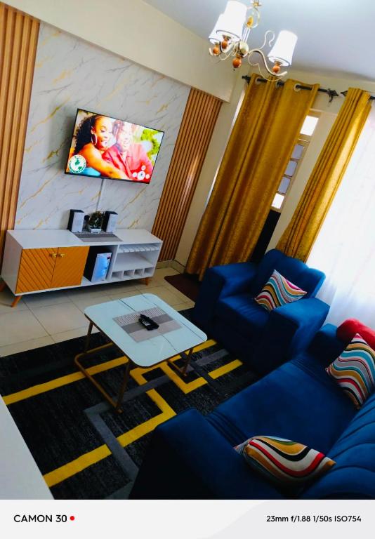a living room with a blue couch and a tv at ONE BEDROOM THIKA ROAD ,TRM DRIVE Homes by Essyruby in Nairobi