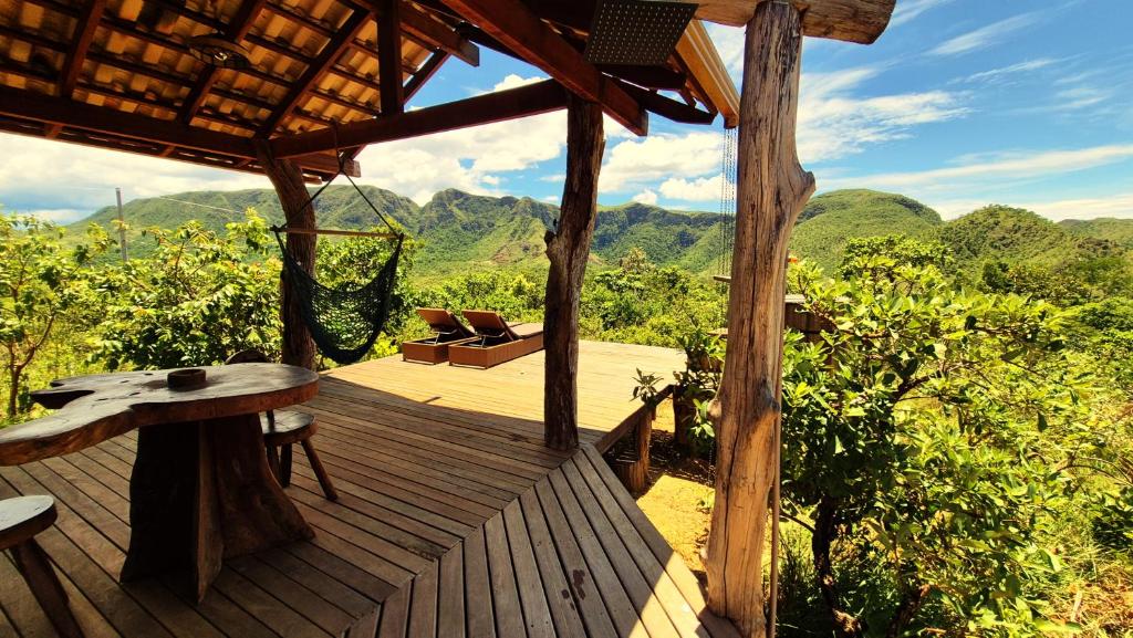 a wooden deck with a hammock and a table at Ecopousada Toca do Guará in Alto Paraíso de Goiás