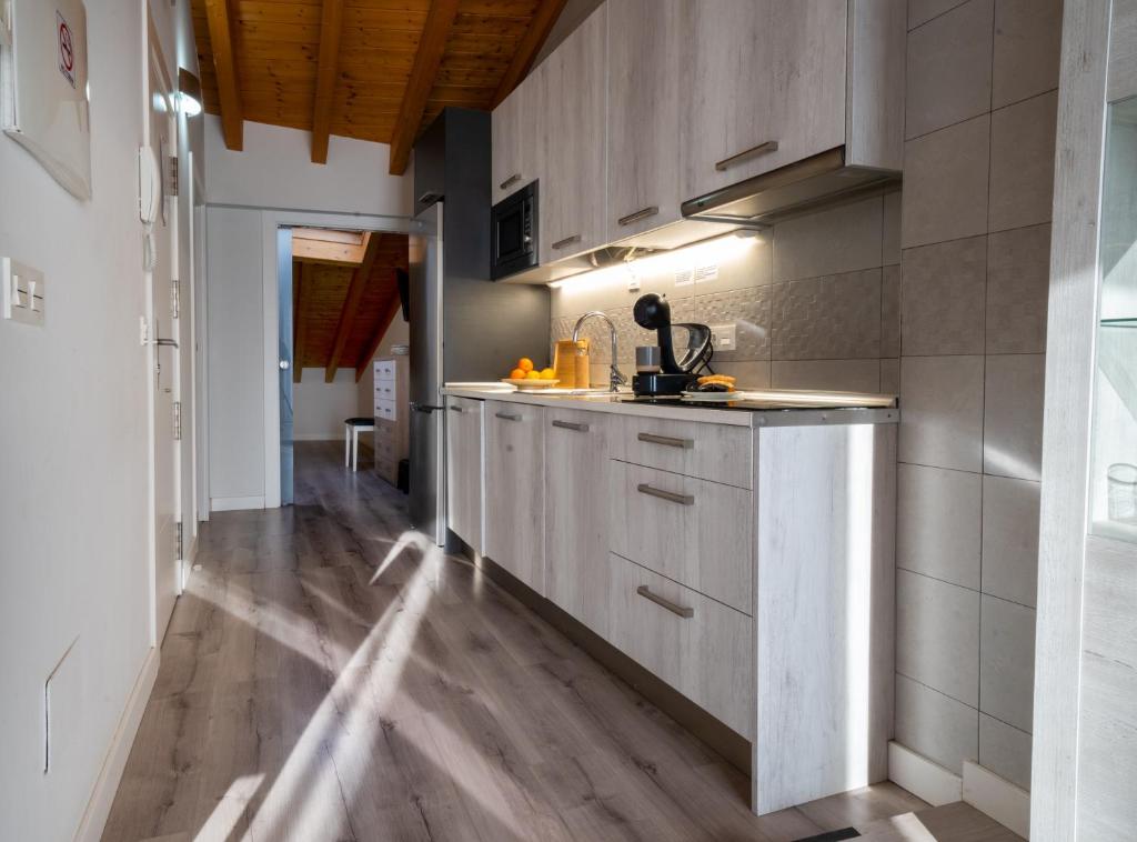 kuchnia z białymi szafkami i drewnianą podłogą w obiekcie Apartamentos Aranda w mieście Aranda de Duero