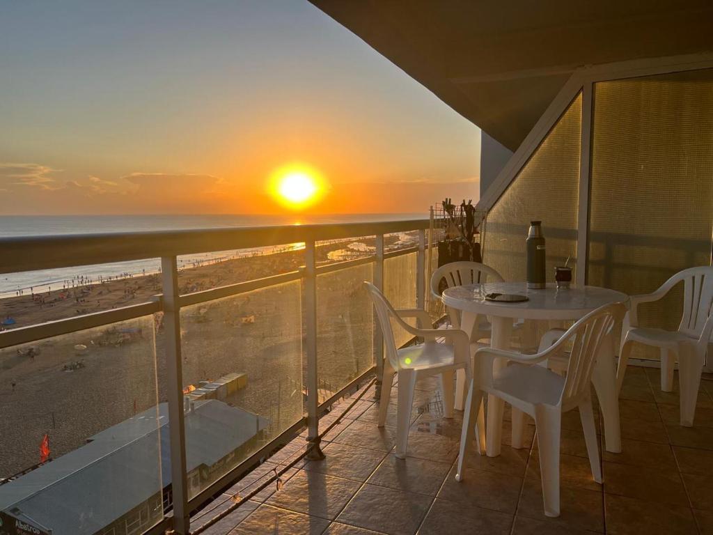 a table and chairs on a balcony with a sunset at Monte Hermoso frente al mar in Monte Hermoso