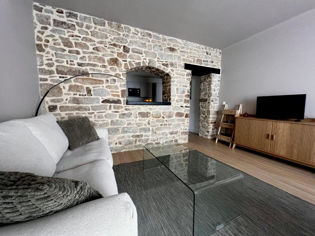 un salon avec un canapé et un mur en pierre dans l'établissement T2 refais à neuf, plein centre ville de Lorient, à Lorient