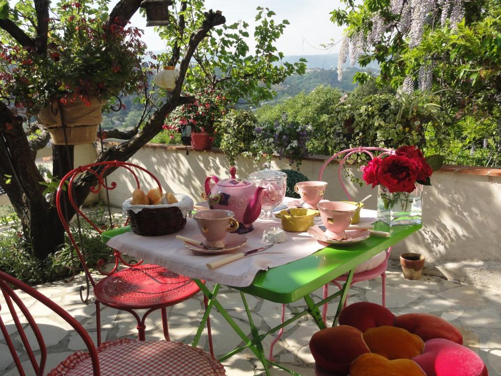 einen Tisch mit Stühlen, Tassen und Blumen darauf in der Unterkunft Les Grimaldines - Maison d'Hôtes in Cagnes-sur-Mer