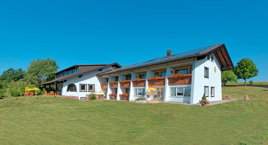 a large white house on a grassy hill at Landgasthaus Sonne in Freudenstadt