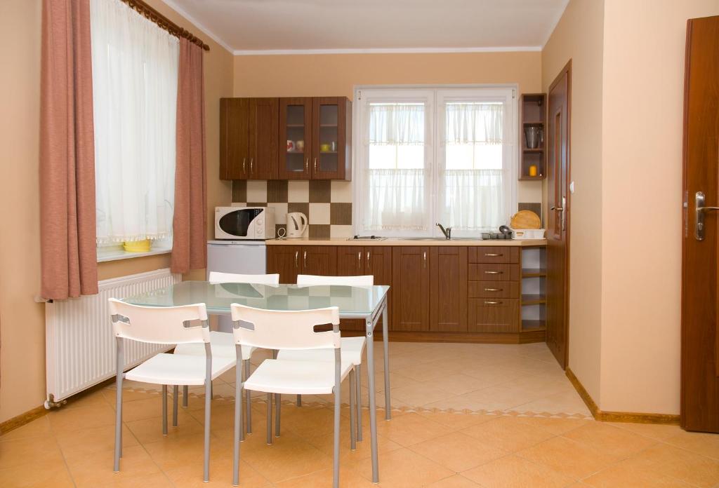 cocina con mesa de cristal y sillas blancas en Family Homes - Sand Apartments, en Władysławowo