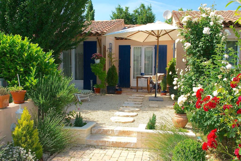 a garden with a house with an umbrella and flowers at B&B Villa Viva Vitale in Pierrevert
