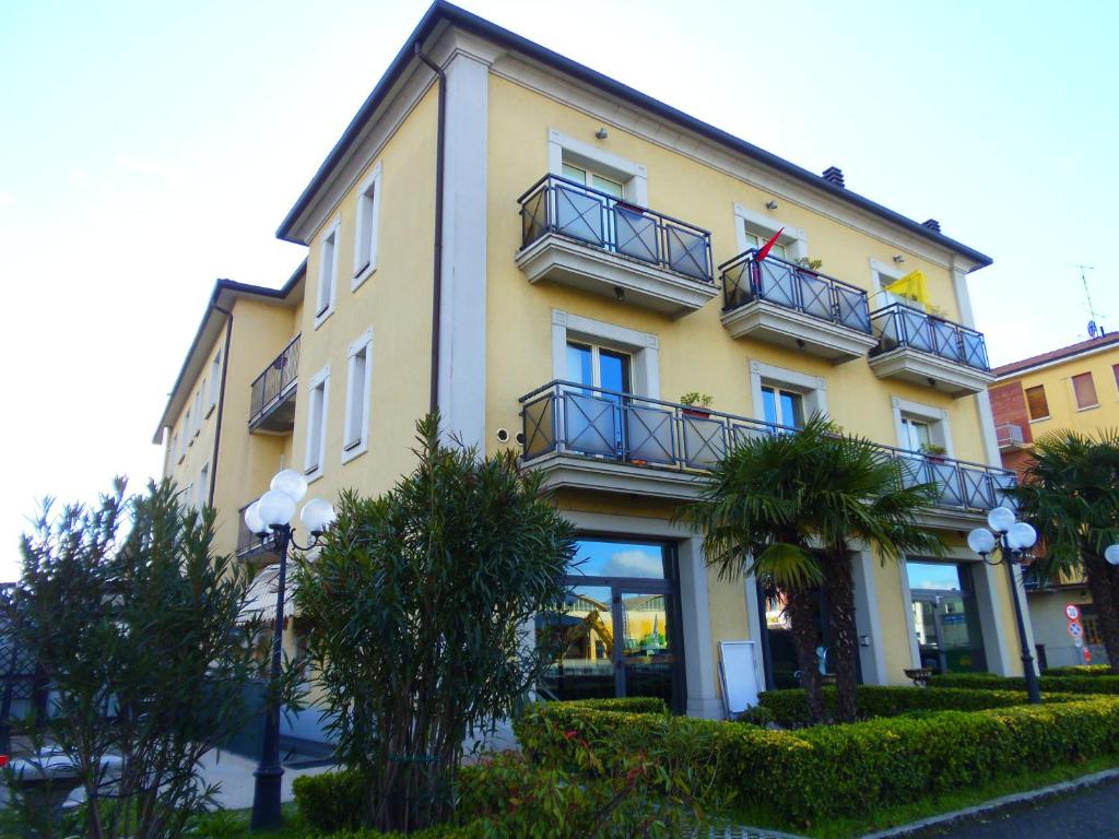 ein gelbes Gebäude mit Balkonen und Bäumen davor in der Unterkunft Albergo Sirena in Bazzano Bologna