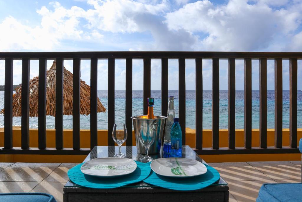 una mesa con platos y copas de vino en el balcón en Beach front luxury living - 2 bedroom condo with sea view, en Jan Thiel