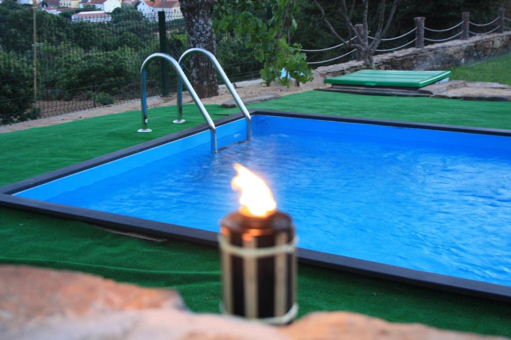 une bougie éclairée en face d'une piscine dans l'établissement Casas do Bairrinho, à Sambade