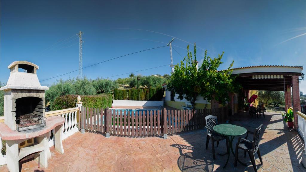 eine Terrasse mit einem Kamin, einem Tisch und Stühlen in der Unterkunft Casa Rural El Cuco in Luque