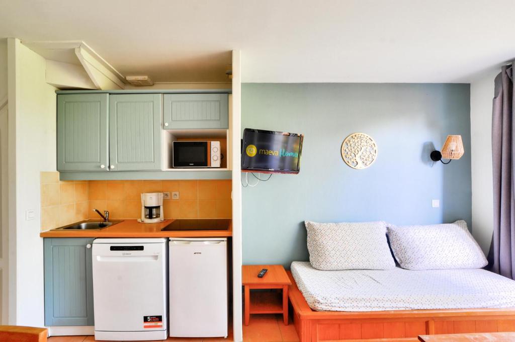 Elle comprend une petite cuisine avec des placards verts et un réfrigérateur blanc. dans l'établissement La résidence du Lac - maeva Home - Appartement 2 pièces 5 personnes - Sélection MAE-3921, à Monflanquin
