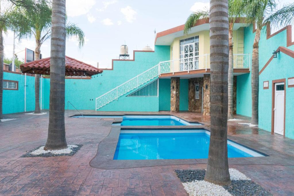 une piscine devant une maison avec des palmiers dans l'établissement Casa Vacacional en calvillo, à El Rodeo