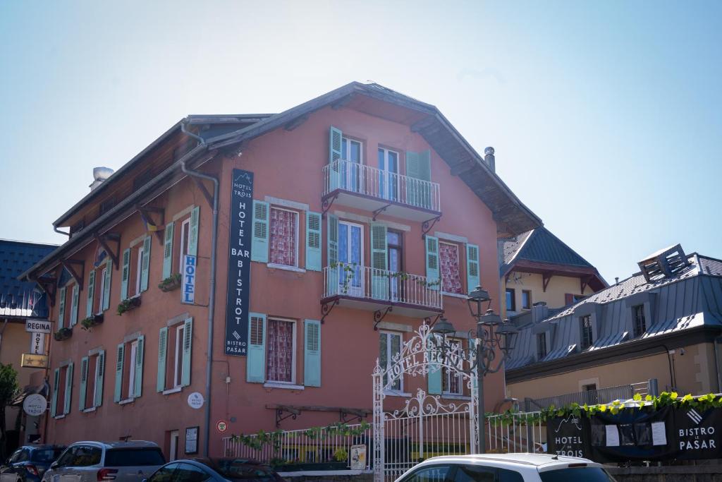 a pink building with cars parked in front of it at Hotel de Trois St Gervais in Saint-Gervais-les-Bains
