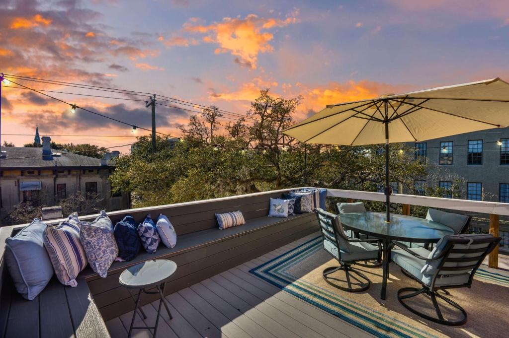 a balcony with a table and chairs and an umbrella at Penthouse! Rooftop Deck Movie Room Walkable-4 in Savannah