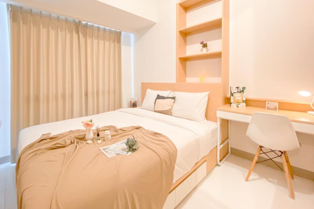 a bedroom with a bed and a desk and a chair at Good and Cozy Stay 2BR Tokyo Riverside PIK 2 Apartment By Travelio in Tangerang