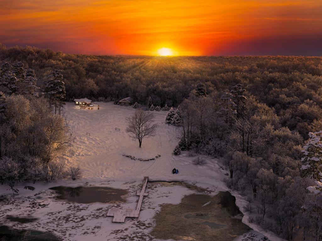 an aerial view of a snow covered field with the sunset at 2 Lake Cabins Poolhottub Game Room & Courts in Highland Lake