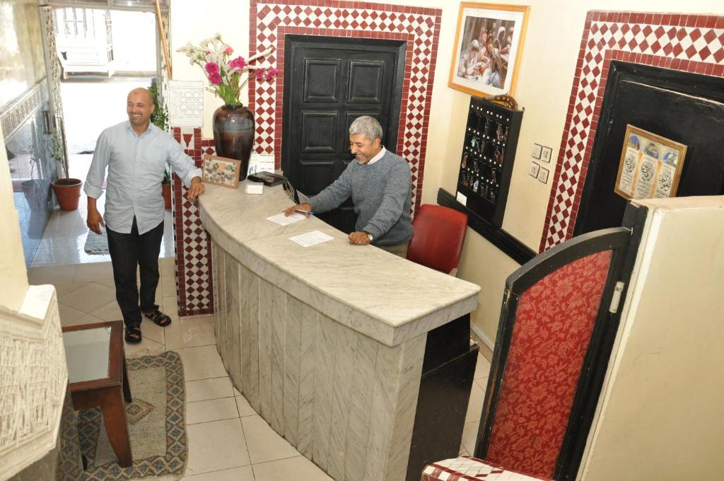 dos hombres parados en un mostrador en una tienda en Hotel Boustane, en Casablanca