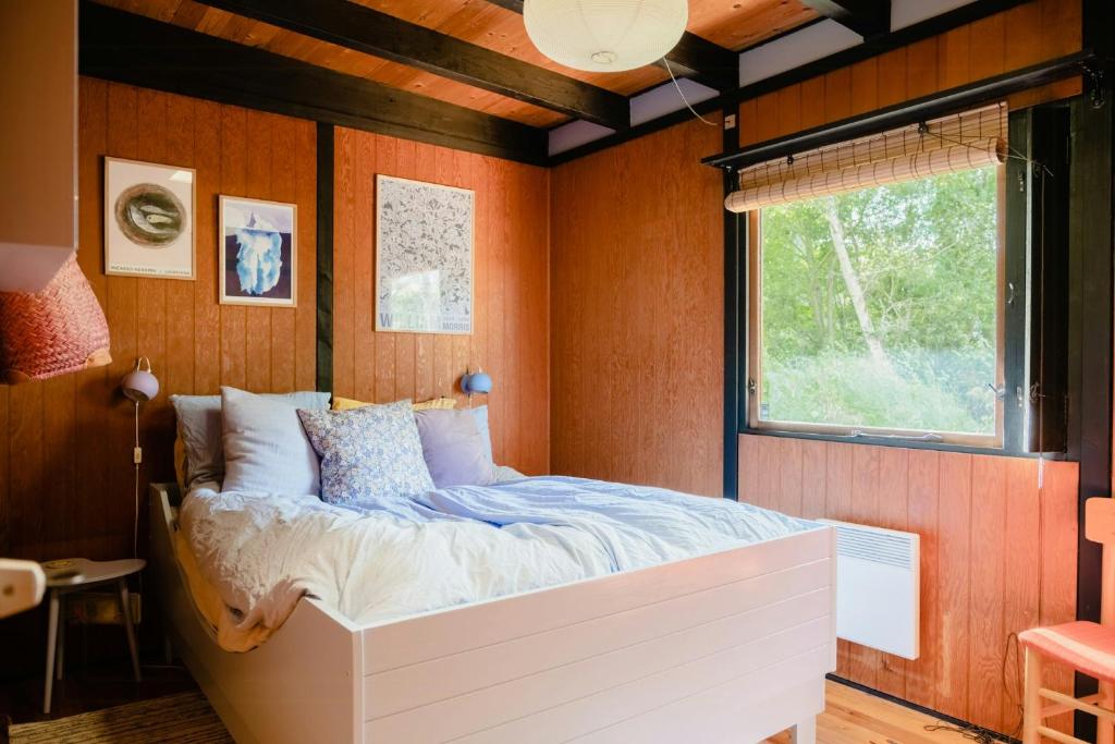 une chambre avec un lit dans une pièce avec une fenêtre dans l'établissement 60S Cabin With Vintage Finds And Wild Surroundings, à Tjørneholm