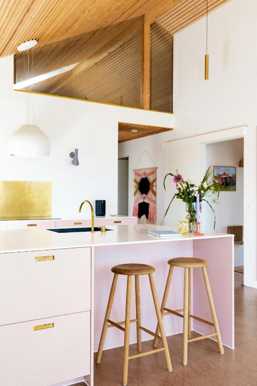 a kitchen with white counters and two stools at Newly Built Summer House With Sea View in Haderslev