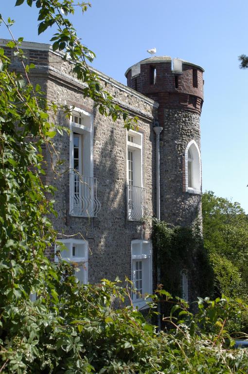 an old brick building with a tower with windows at Domaine Saint Clair - Le Donjon in Étretat