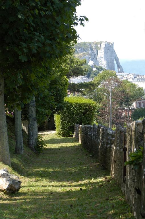 a stone wall with trees and a mountain in the background at Domaine Saint Clair - Le Donjon in Étretat