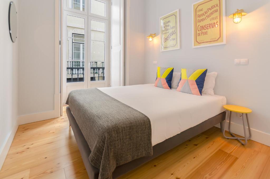 ein Schlafzimmer mit einem großen weißen Bett mit bunten Kissen in der Unterkunft Casas da Baixa - Lighthouse Apartments in Lissabon