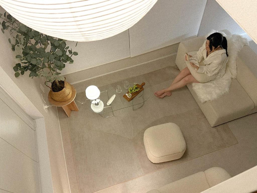 a woman sitting on a couch reading a book at Soansosa Duplex of designer in Bucheon