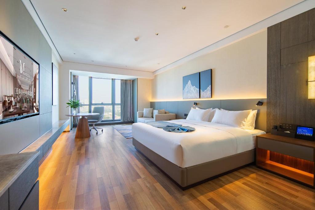 una camera d'albergo con un letto grande e una scrivania di 青岛西海岸城市阳台Madison酒店 a Qingdao
