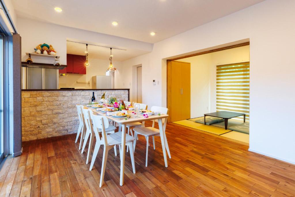 een keuken en eetkamer met een tafel en stoelen bij 美ら海水族館まで車で5分 広い庭 最大10名 まるまる貸し切り 花の雲 in Motobu
