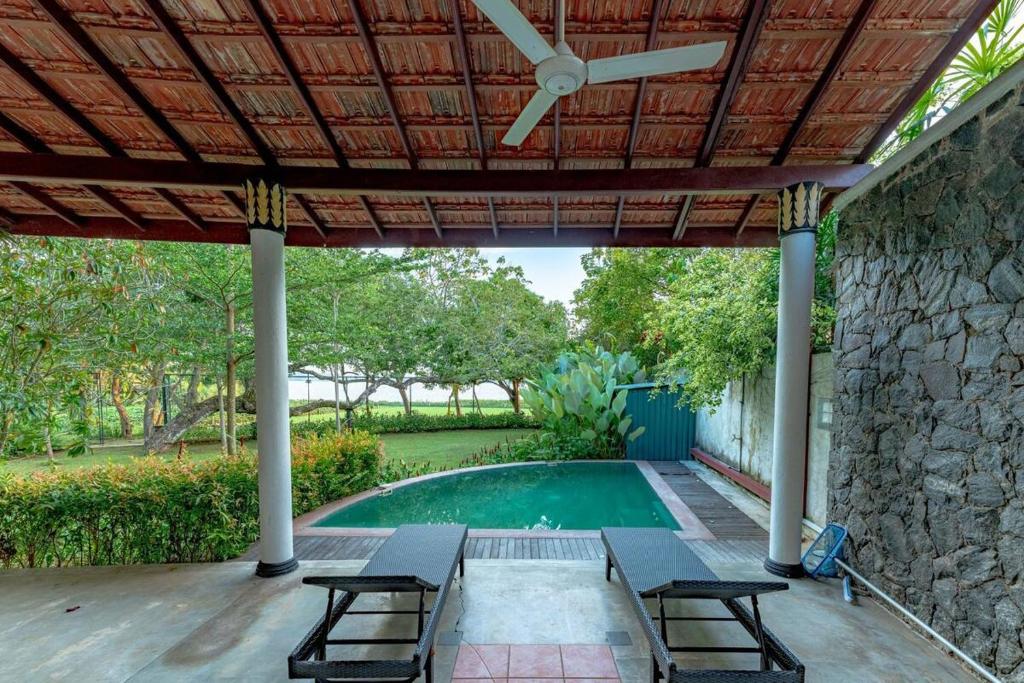 un patio avec tables et chaises et une piscine dans l'établissement Adaaran Villa Bolgoda, à Moratuwa