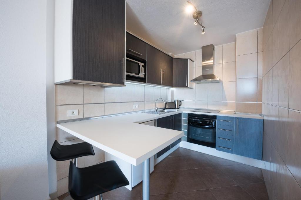 a kitchen with a white counter and blue cabinets at Paloma Beach Apartments in Los Cristianos