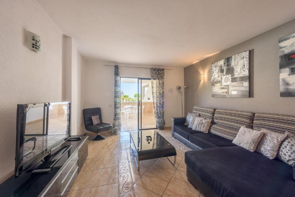 a living room with a blue couch and a television at Paloma Beach Apartments in Los Cristianos