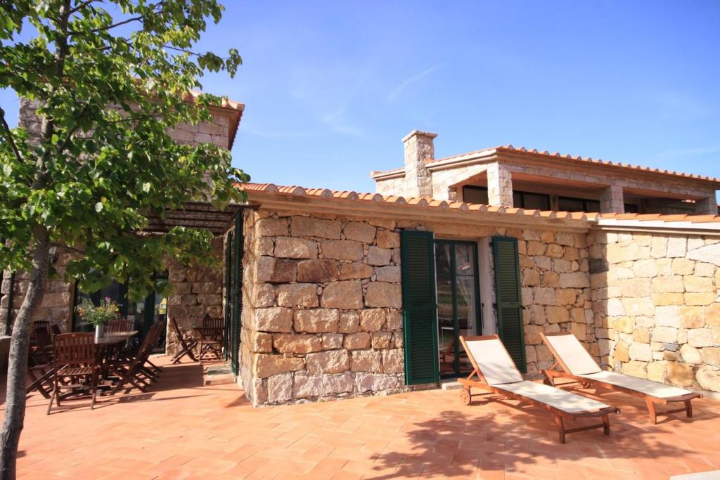 ein Steingebäude mit zwei Stühlen und einem Haus in der Unterkunft Les anciennes écuries, belle villa pour 12 personnes au coeur d'un vignoble avec piscine in Sartène