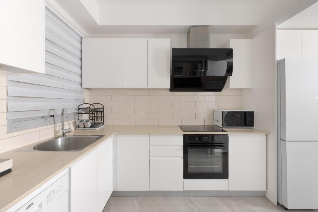 eine weiße Küche mit Spüle und Kühlschrank in der Unterkunft Sahara - Designed Duplex with a private pool in Eilat