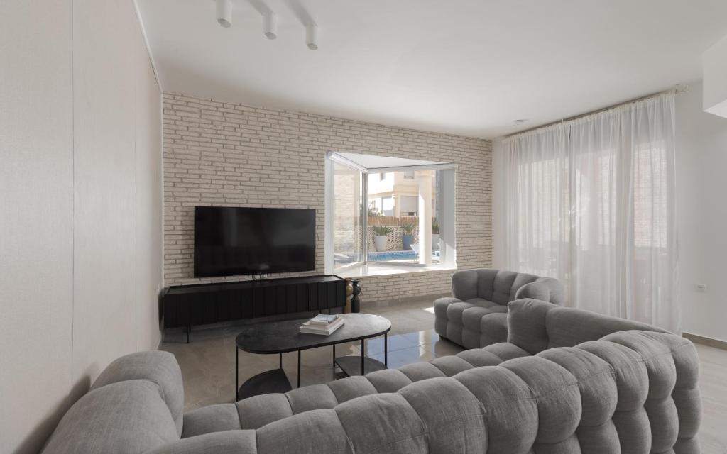 ein Wohnzimmer mit Couch und Fernseher in der Unterkunft Sahara - Designed Duplex with a private pool in Eilat