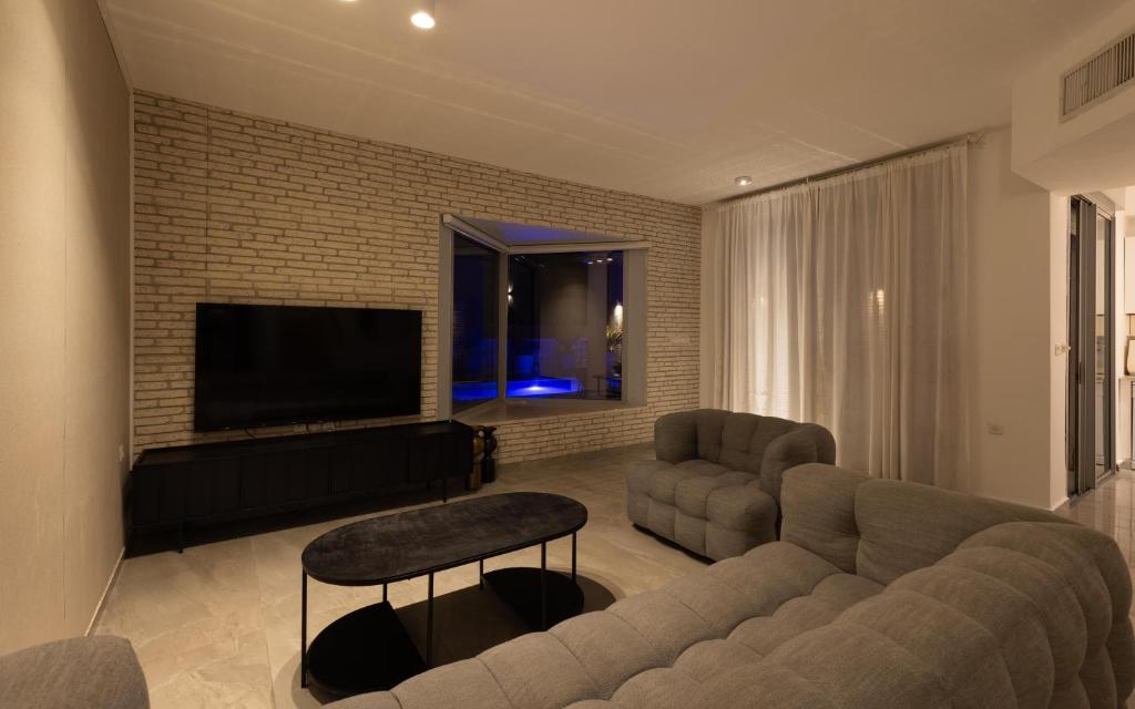 ein Wohnzimmer mit Couch und Flachbildfernseher in der Unterkunft Sahara - Designed Duplex with a private pool in Eilat