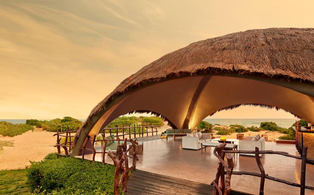 un resort con tetto di paglia, tavoli e sedie di Uga Chena Huts - Yala - All Inclusive a Yala