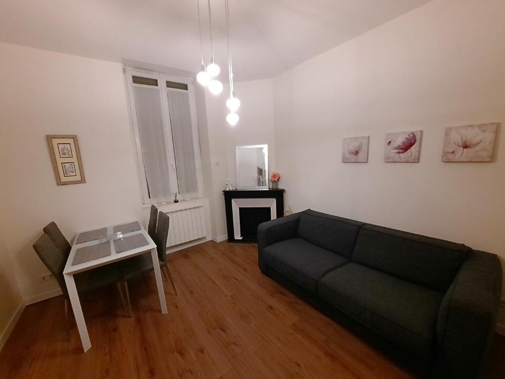 un salon avec un canapé noir et une table dans l'établissement Le Hoche - Apt 4 Personnes, 1 ch, Proche Gare, à Dijon