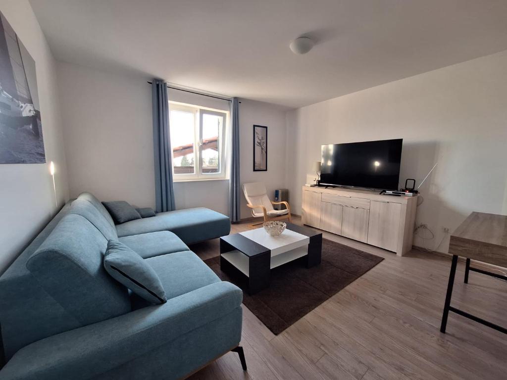 a living room with a blue couch and a tv at Sailing Forever Bungalow in Kaštela