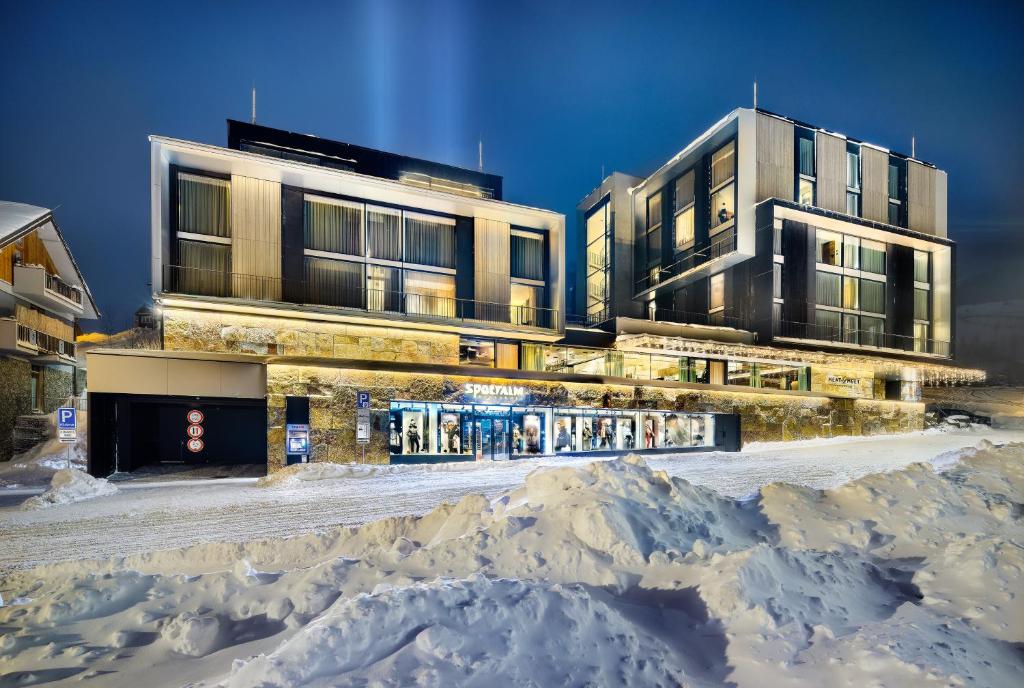 un edificio con un montón de nieve delante de él en Grand Hotel Hradec, en Pec pod Sněžkou