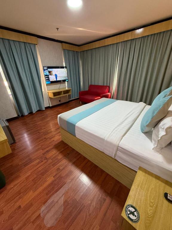 a bedroom with a large bed and a red chair at Strand Hotel in Abu Dhabi