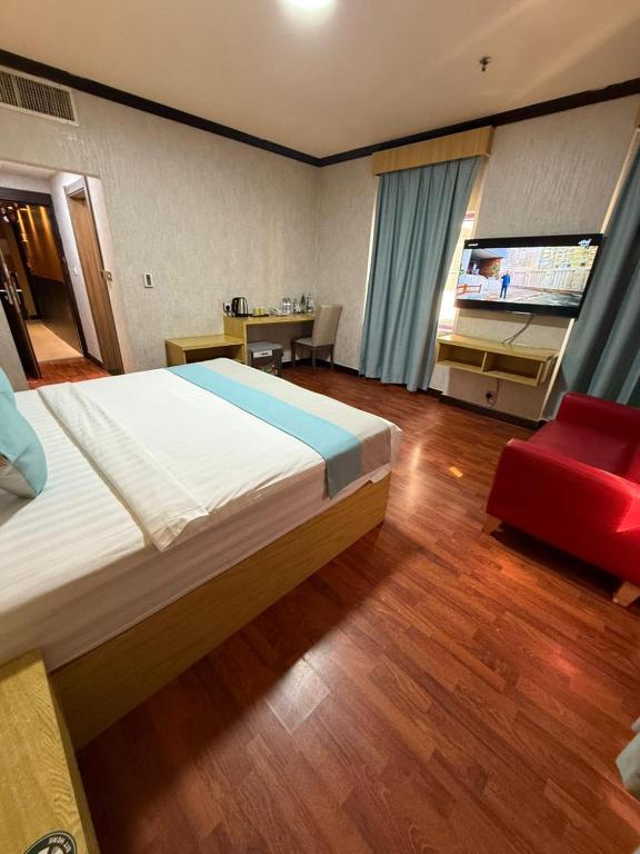 a bedroom with a large bed and a red chair at Strand Hotel in Abu Dhabi