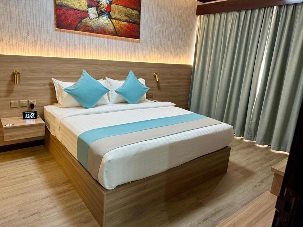 a bedroom with a large bed with blue pillows at Strand Hotel in Abu Dhabi